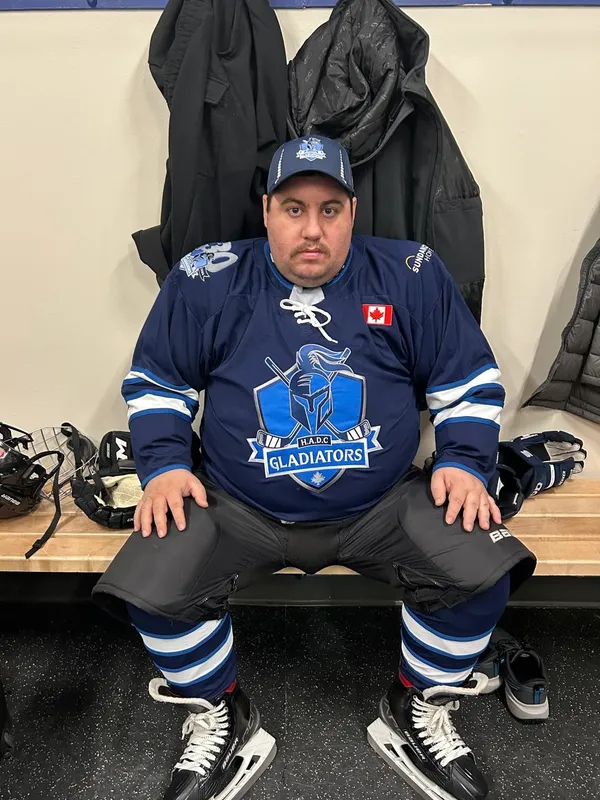 A Gladiators player in team jersey and skates in the dressing room